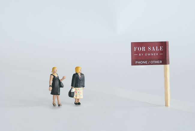 Small model figures beside a for sale sign