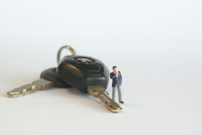 Small model figure standing beside car keys