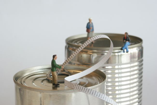 Small model figures standing on metal food tins
