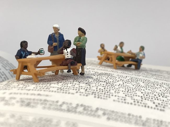 Small model figures sitting on park benches