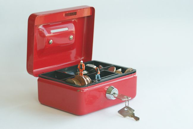Small model figure sitting on a red box with key