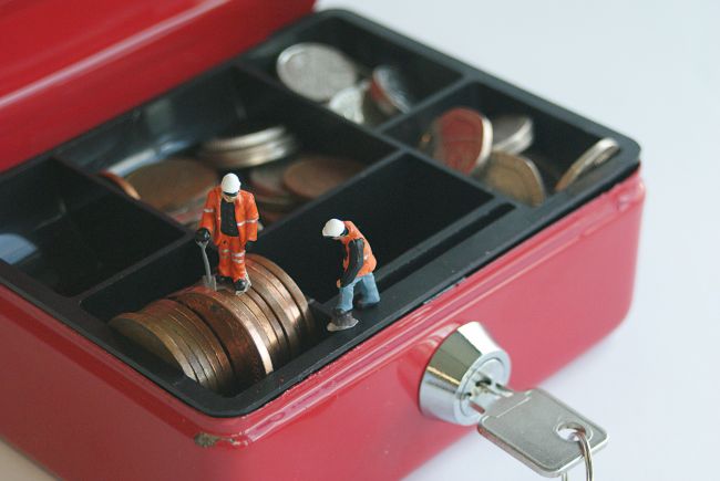 Small model figures working inside a red box with key