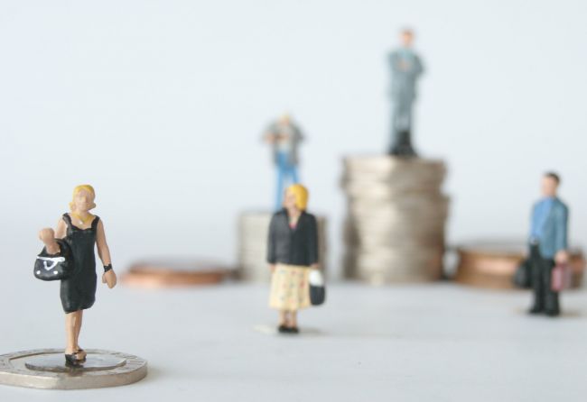 Small model figures walking past stacks of coins