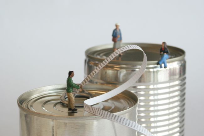 Small model figures sitting on metal food tins