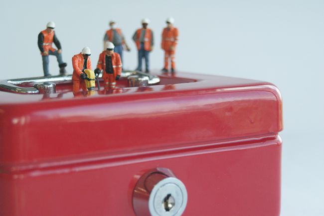 Small model figures standing on locked red box