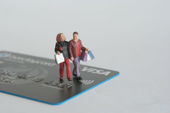 Small model figures walking across a credit card