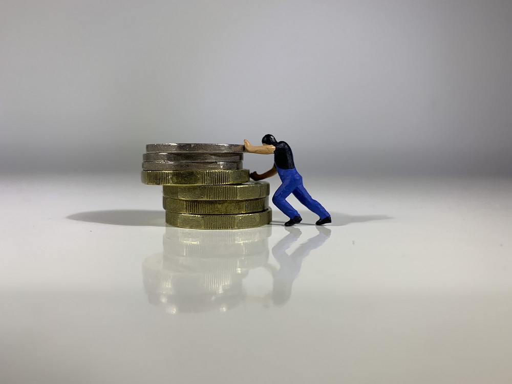 Figurine pushing stack of coins