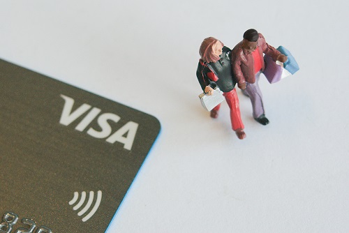 Tiny figurines walk past a credit card